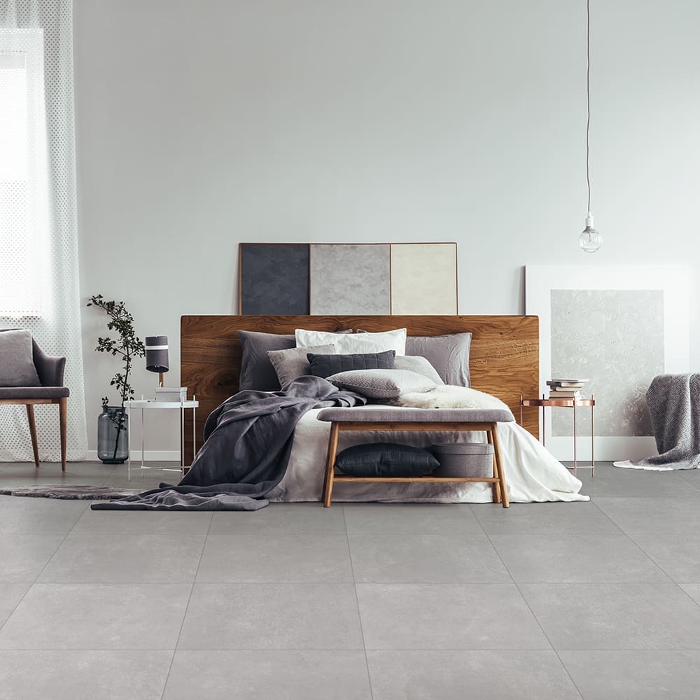 Wooden bench and grey chair near king size bed against white wall with copy space in bedroom with window and paintings