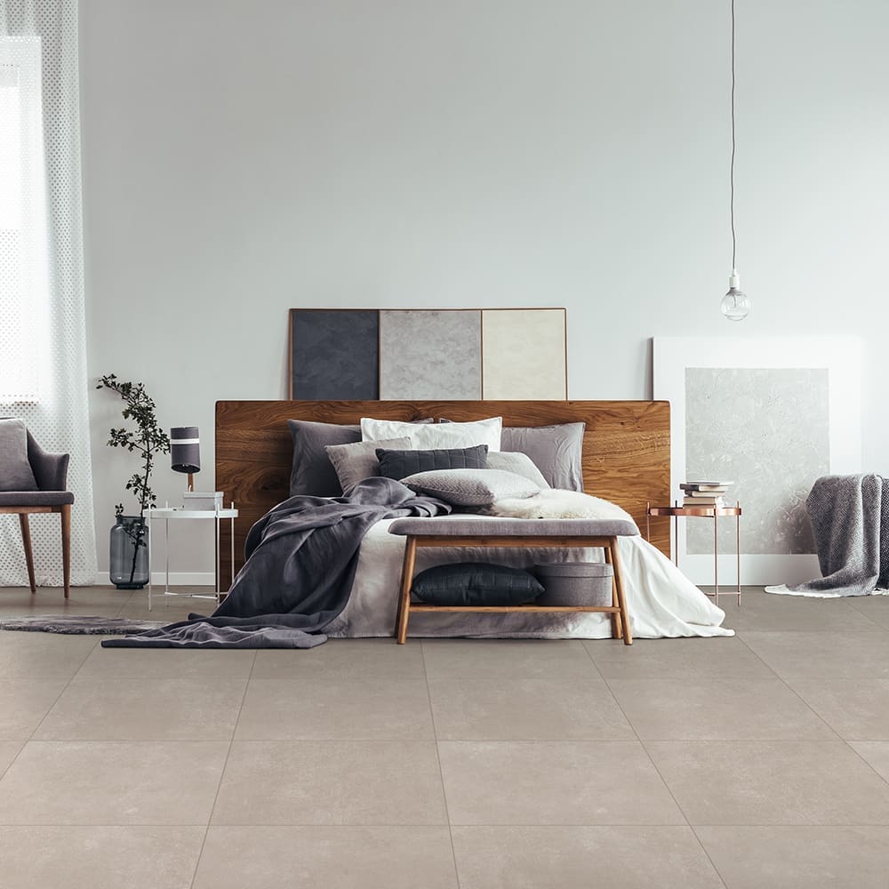 Wooden bench and grey chair near king size bed against white wall with copy space in bedroom with window and paintings